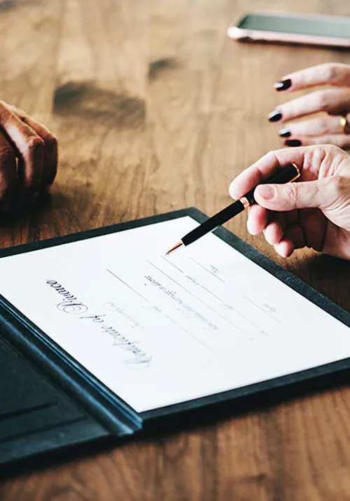 Person signing a document with a pen