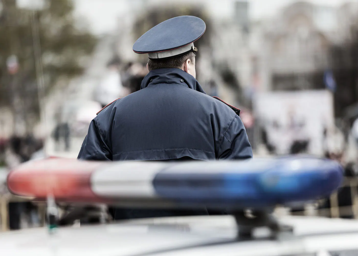 Police officer beside a patrol car’s flashing light bar